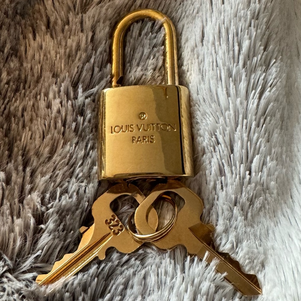 LOUIS VUITTON lock and key gold brass. Includes dust bag.